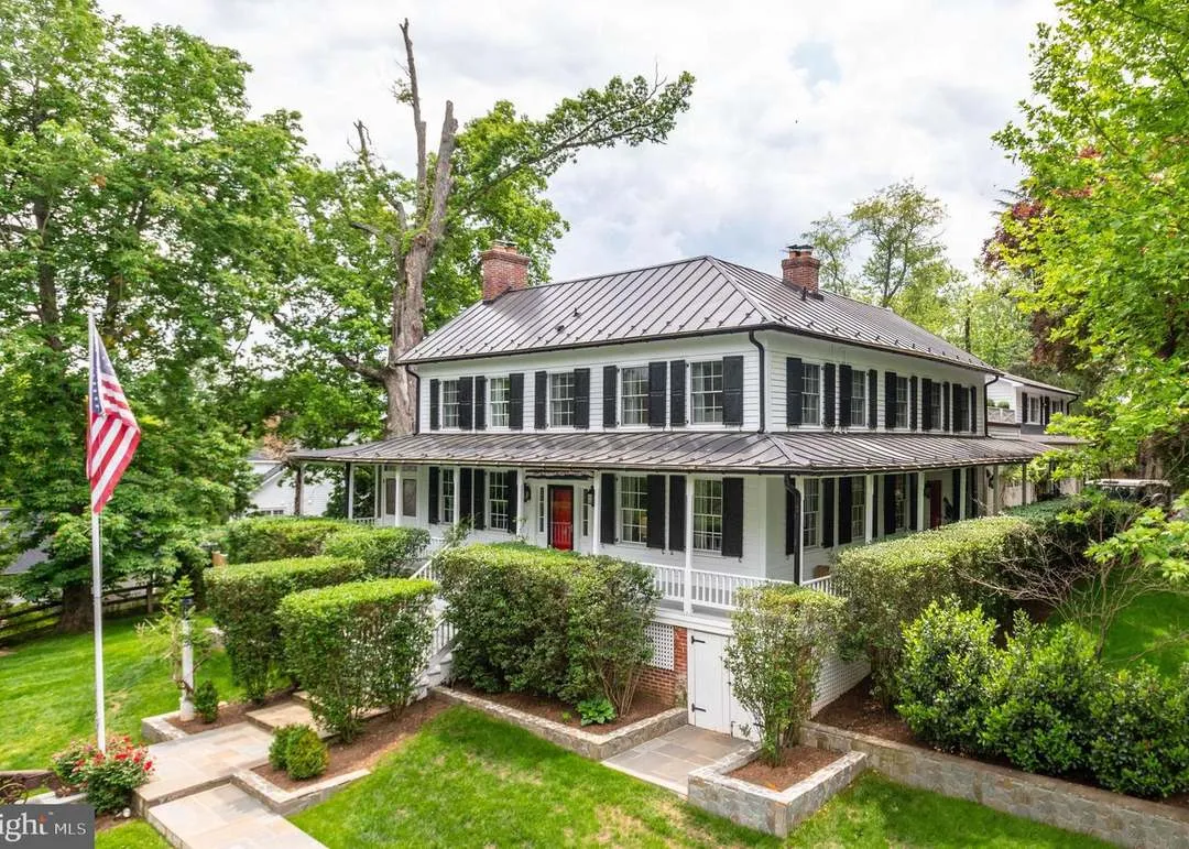 White colonial house with wraparound porch.