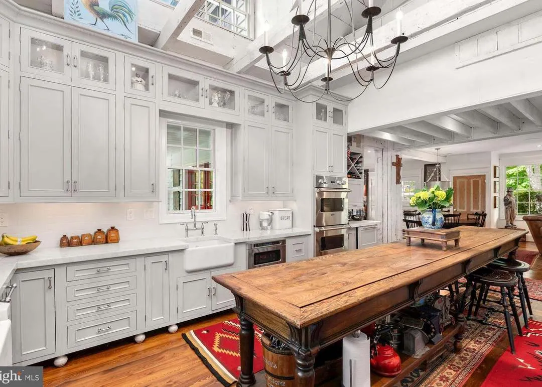 Rustic kitchen with wooden island and chandelier.