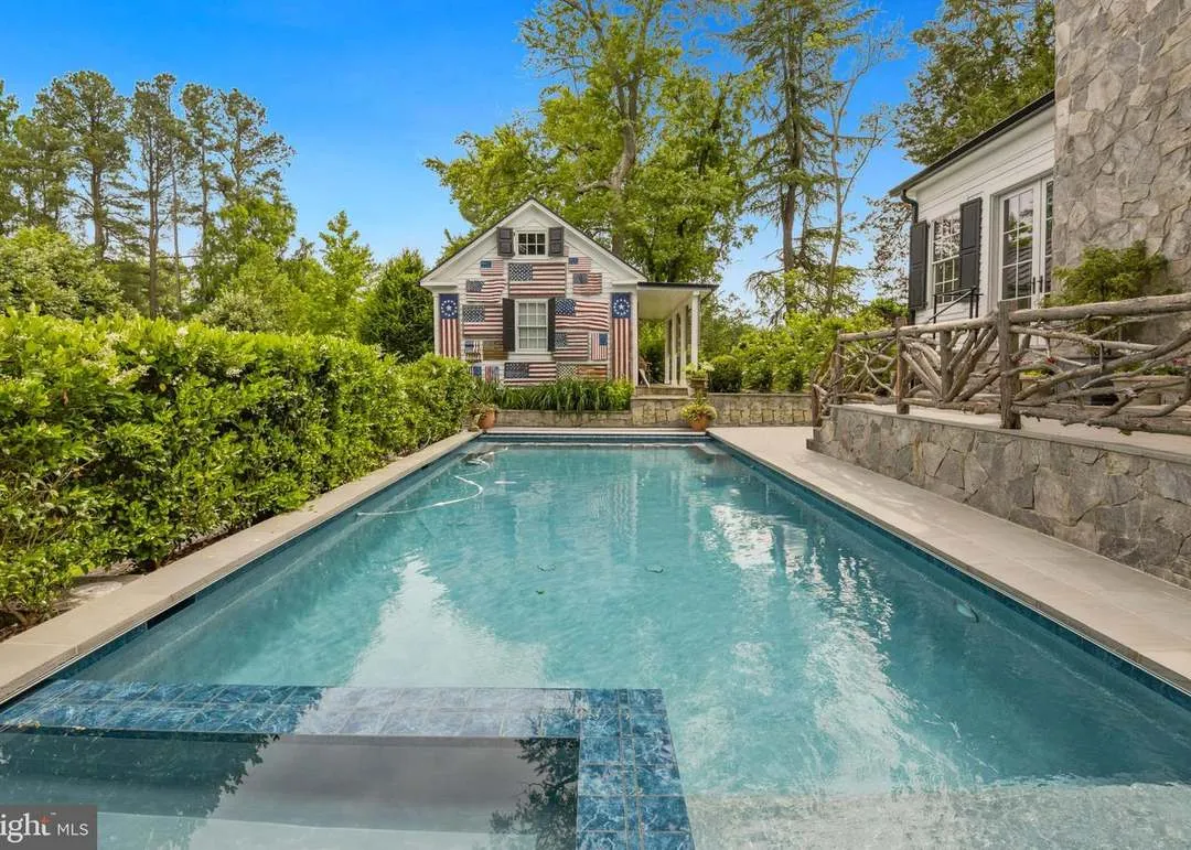 Backyard pool with trees and house view.