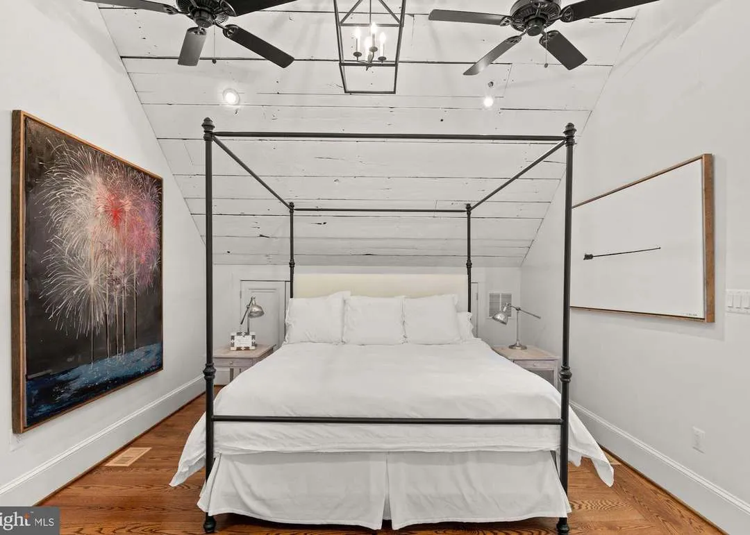 White bedroom with black canopy bed.