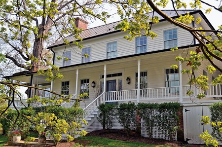 White colonial house with surrounding greenery.