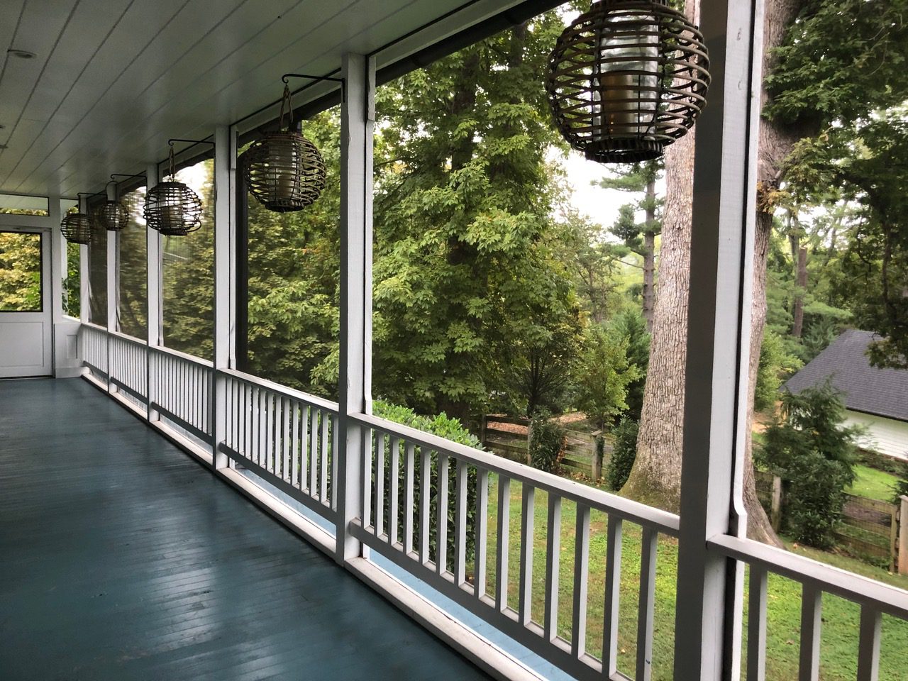 Spacious porch overlooking lush green trees.