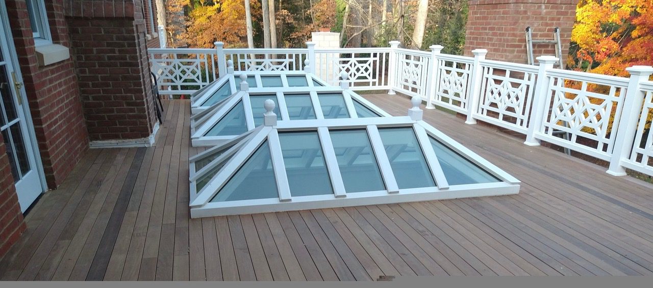 Rooftop deck with glass skylights and railing.