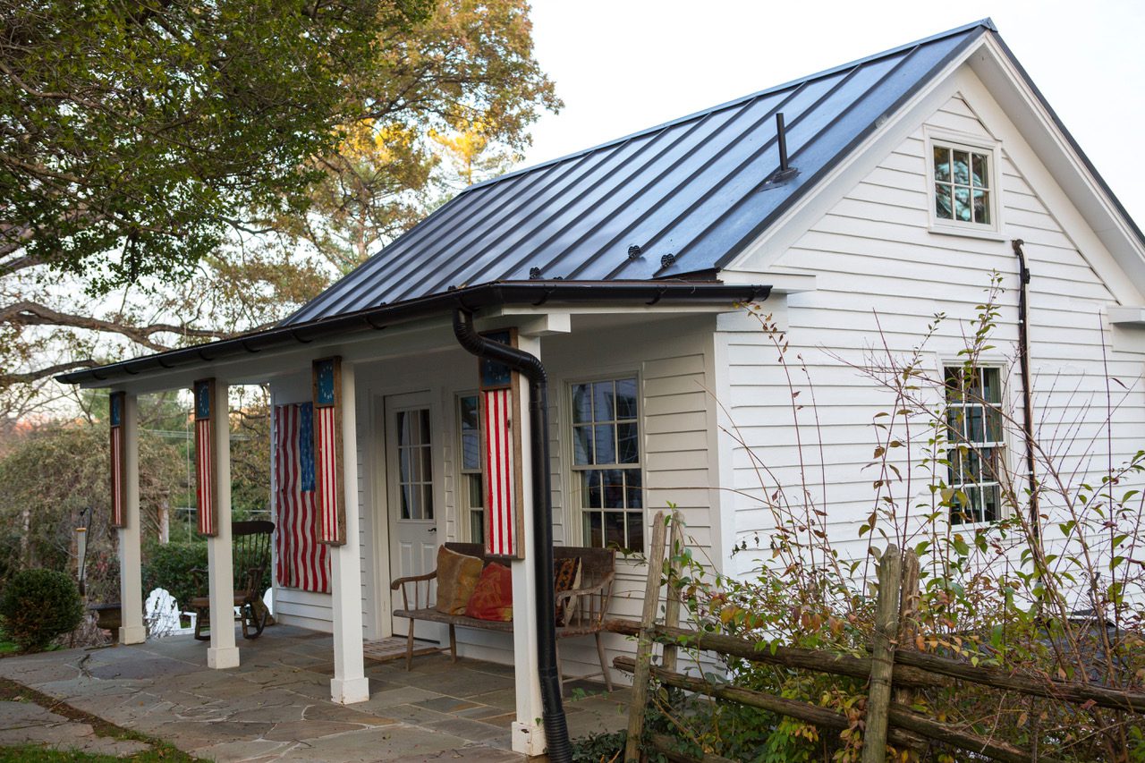 White cottage with flags and porch chairs.