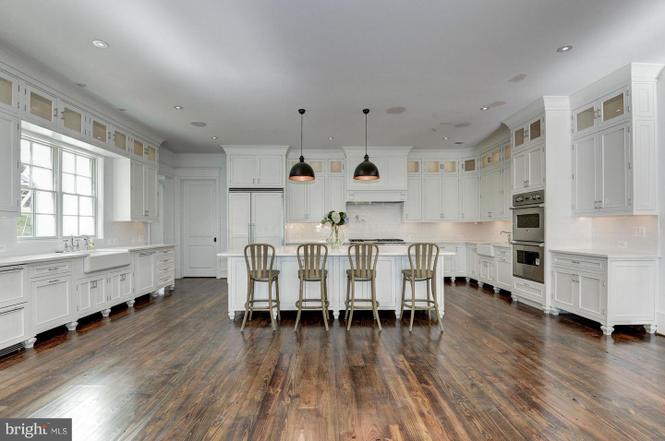 Spacious white kitchen with wooden floor.