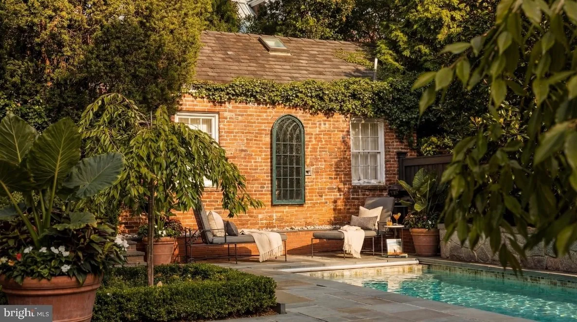 Brick poolside cottage with lush greenery.